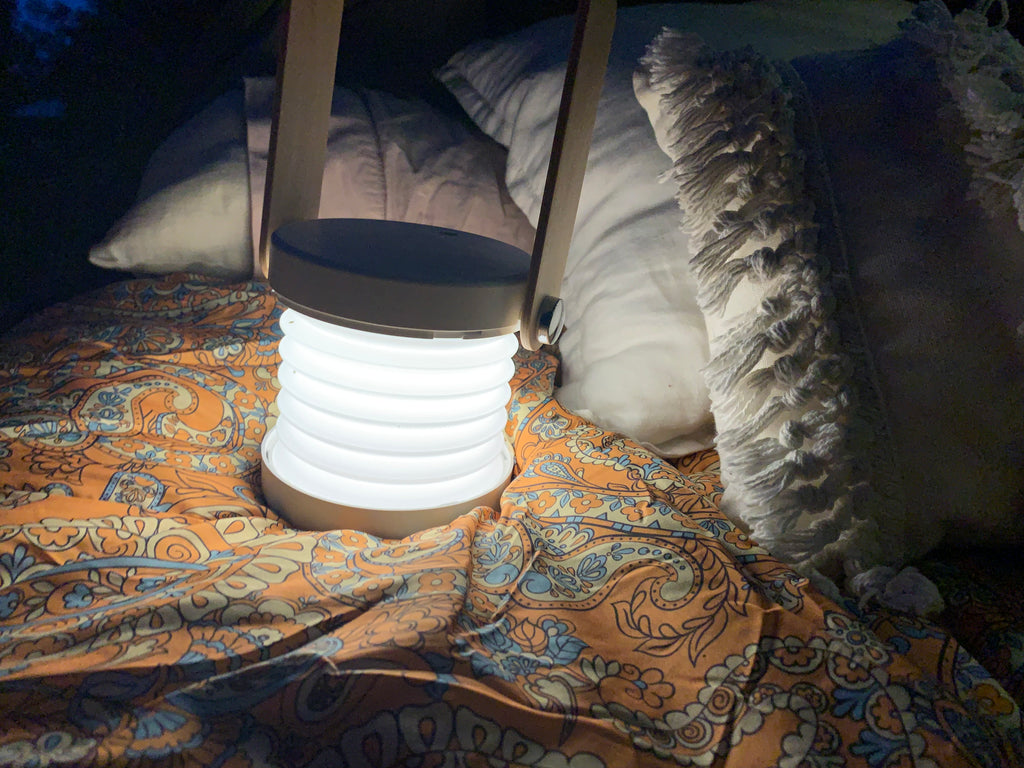 What to take camping. A boho sleeping bag in a swag with a portable camping light. 